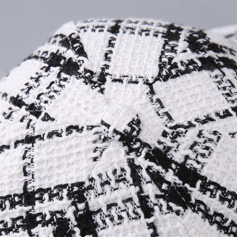 Close-up of the covered top button, crown seams and textured black and white plaid fabric.