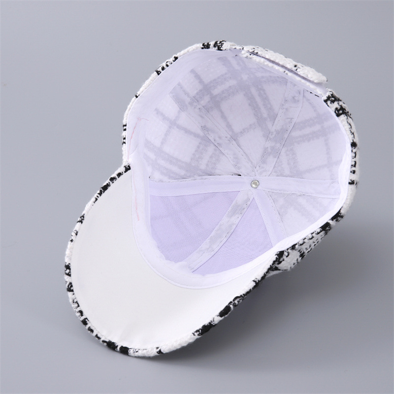 Inside view of the plaid cap showing white lining, seam tapes and the underside of the brim.