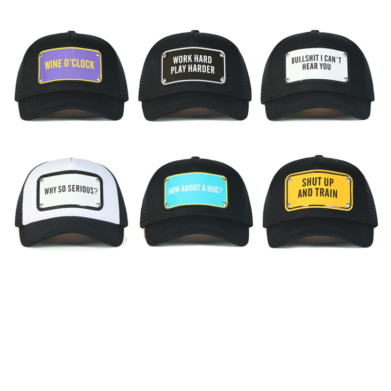 Six mostly black trucker hats with different rectangular slogan badges and curved brims.