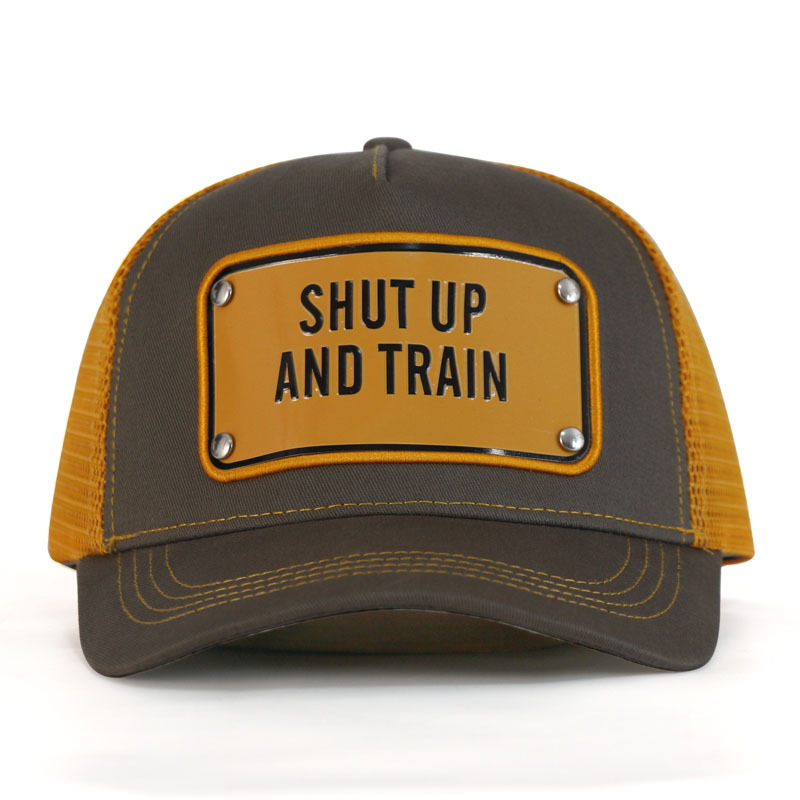 Front view of a brown trucker hat with mustard mesh sides and a yellow Shut Up and Train badge.