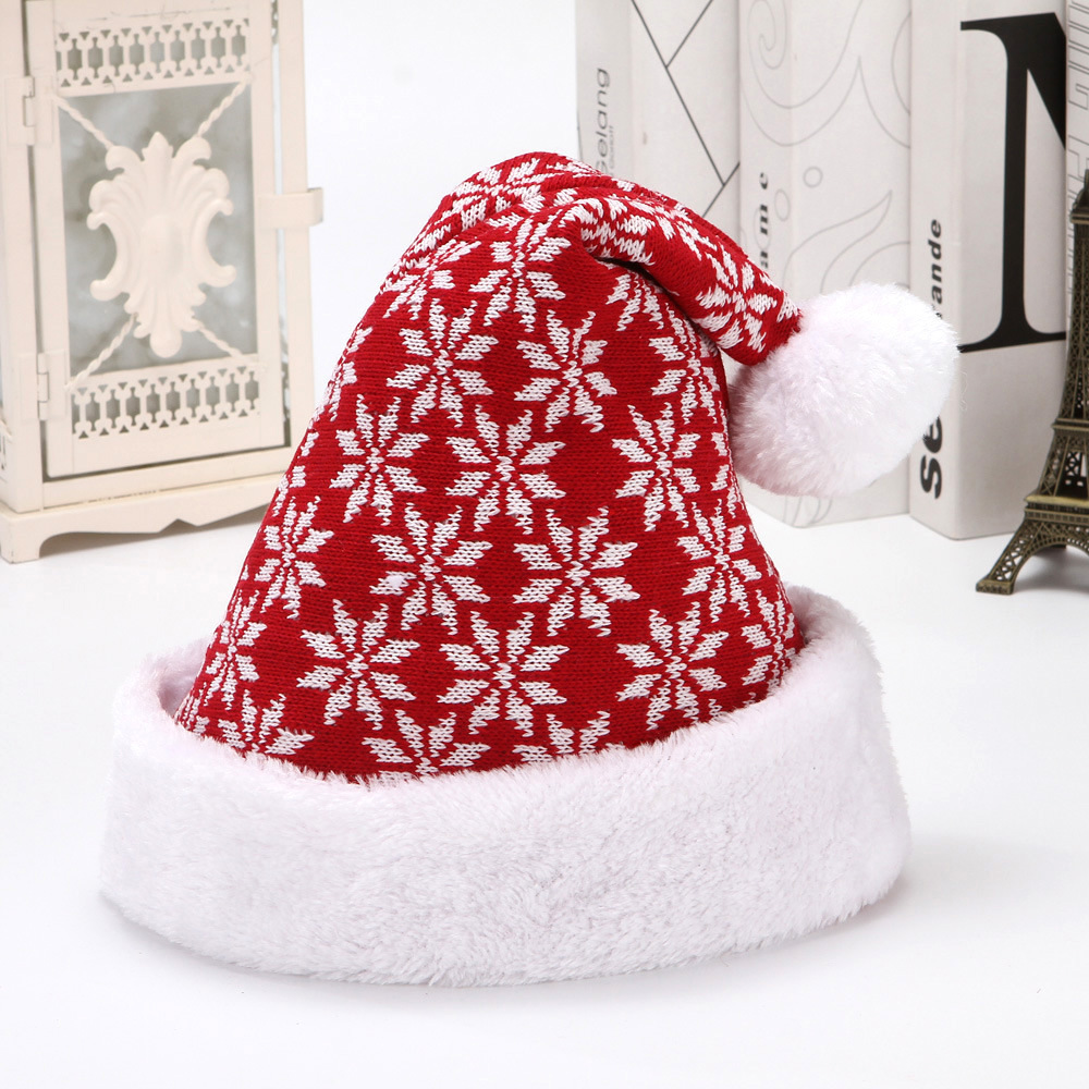 Red knitted Christmas hat with white snowflake motifs, a white plush cuff and a white pom-pom.