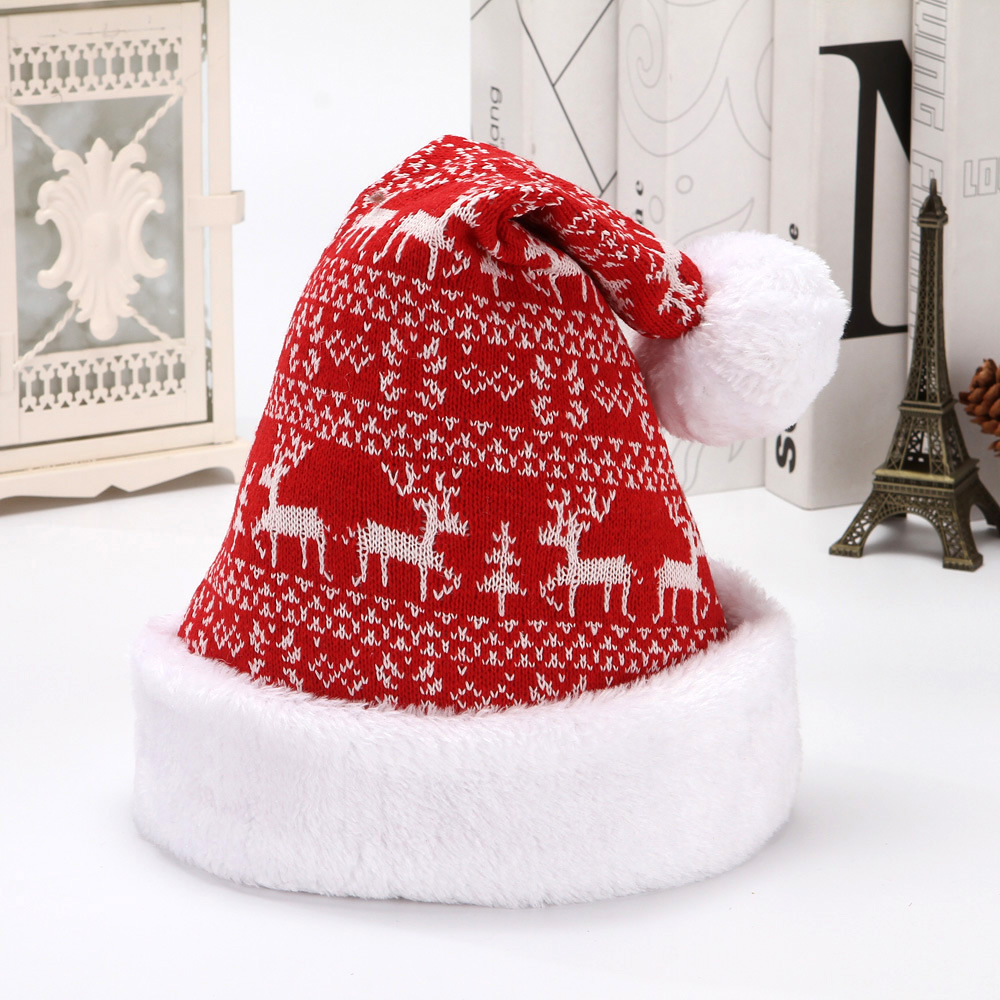 Red knitted Christmas hat with white reindeer and tree motifs, a white plush cuff and pom-pom.