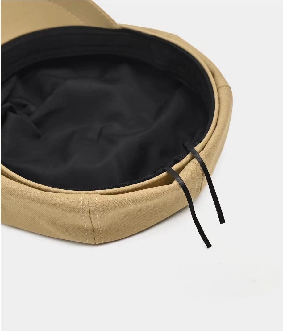 Inside view of a khaki newsboy cap showing black lining and adjustment ties