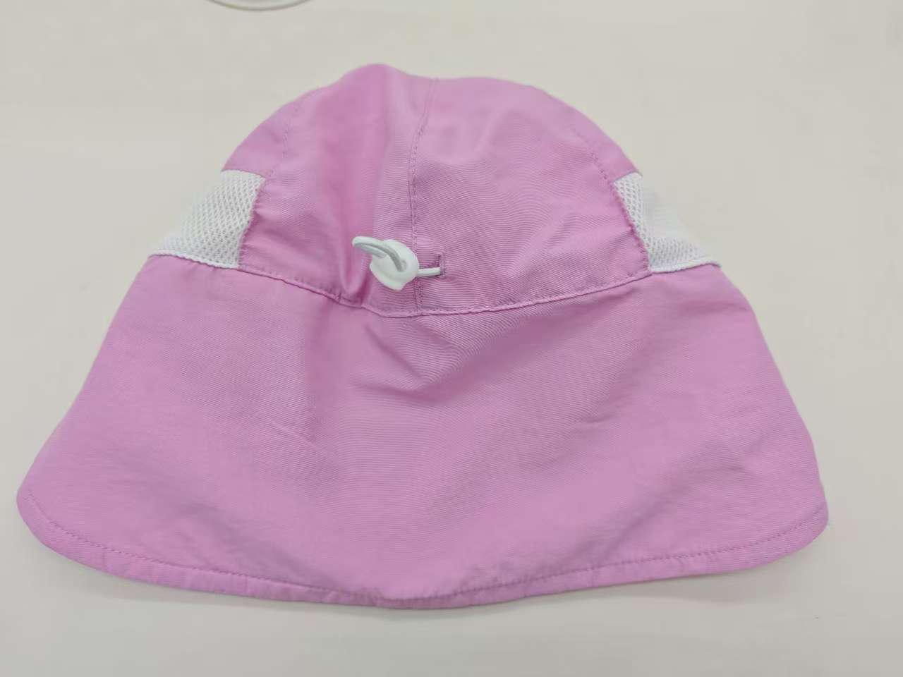 Rear view of a purple kids cap showing the adjustment cord and neck flap.