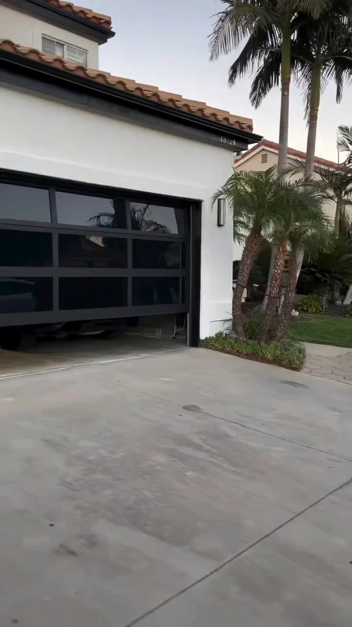 Porte de garage vitrée teintée noire à sens unique offrant une vue dégagée : voyez à l&#39;extérieur, mais pas à l&#39;intérieur grâce à son cadre en aluminium panoramique. 1