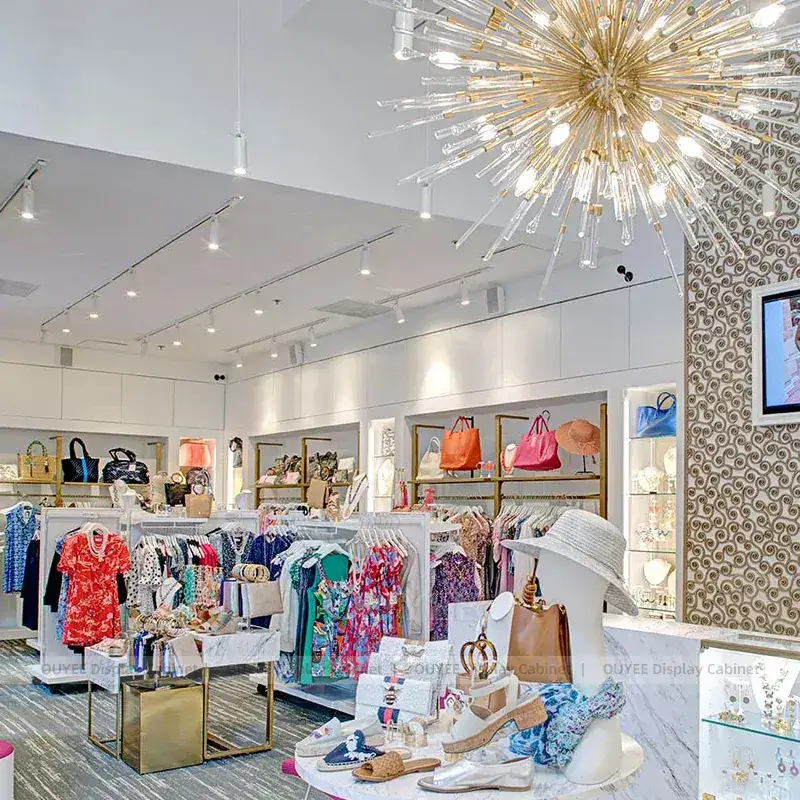 Bright Fashion Boutique Fixtures With Gold Framed Wall Shelves And Center Tables 1