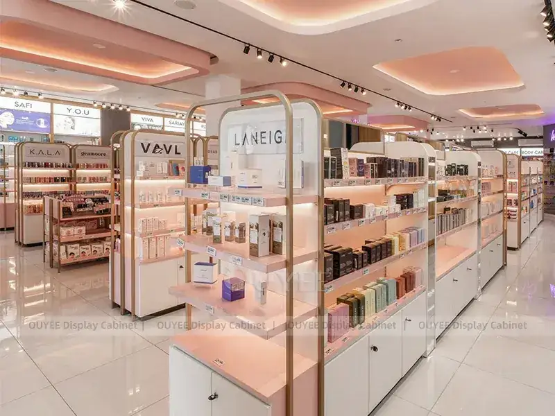 Loja de cosméticos em tons de creme e rosa com teto curvo e ilhas. 1