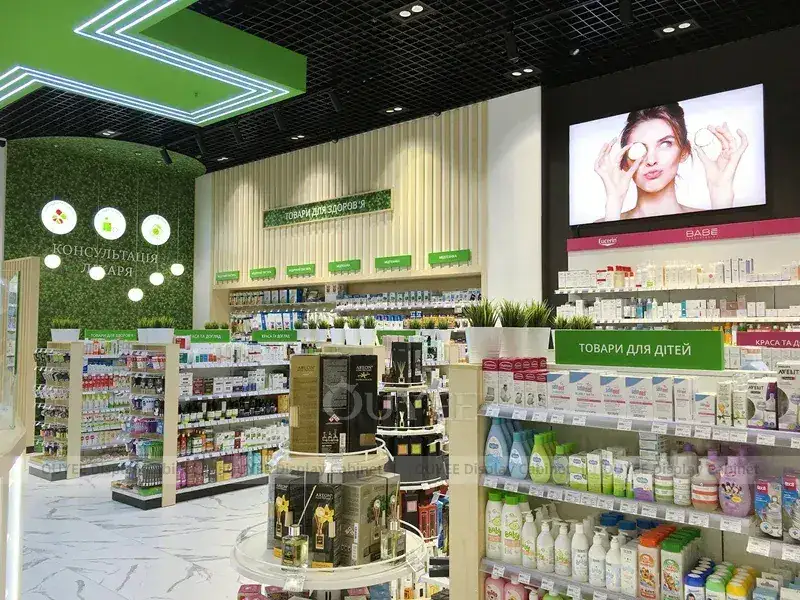 Bancone da farmacia verde e bianco con mensole a parete illuminate. 1