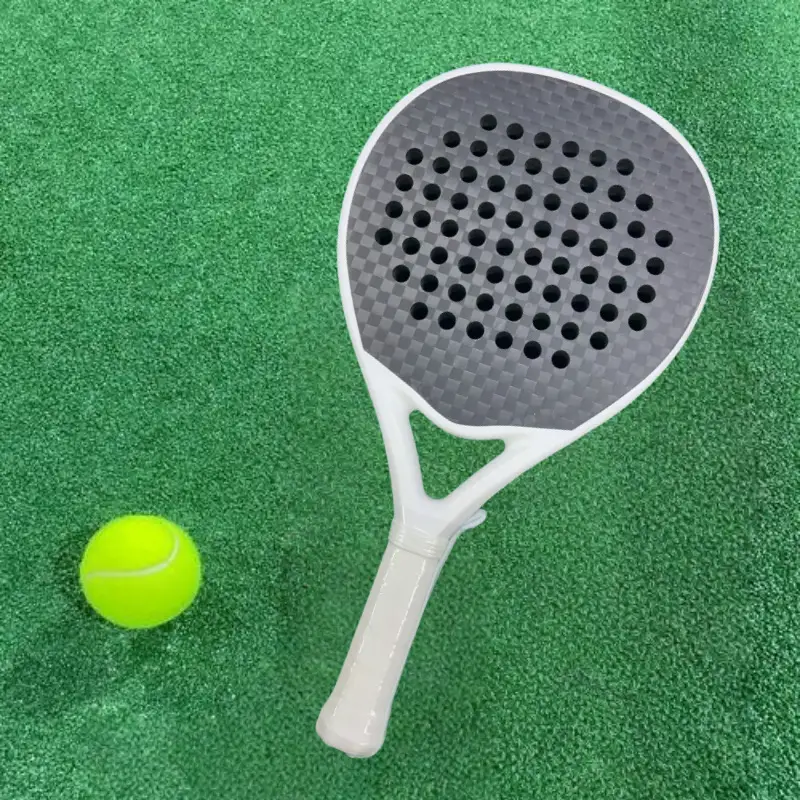 Pala de pádel de carbono de gama básica en pista verde con pelota de tenis