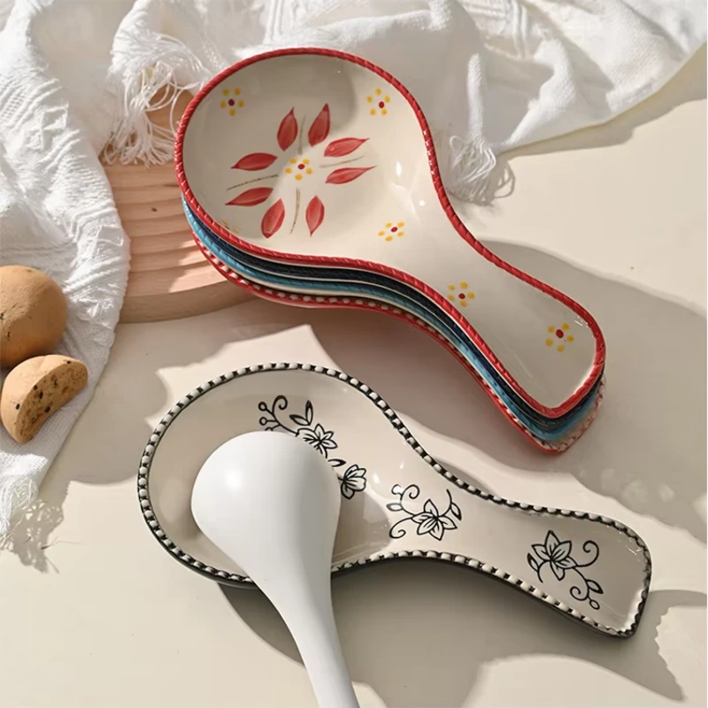 Hand painted floral ceramic spoon rest, decorative kitchen spoon holder on beige table with linen cloth