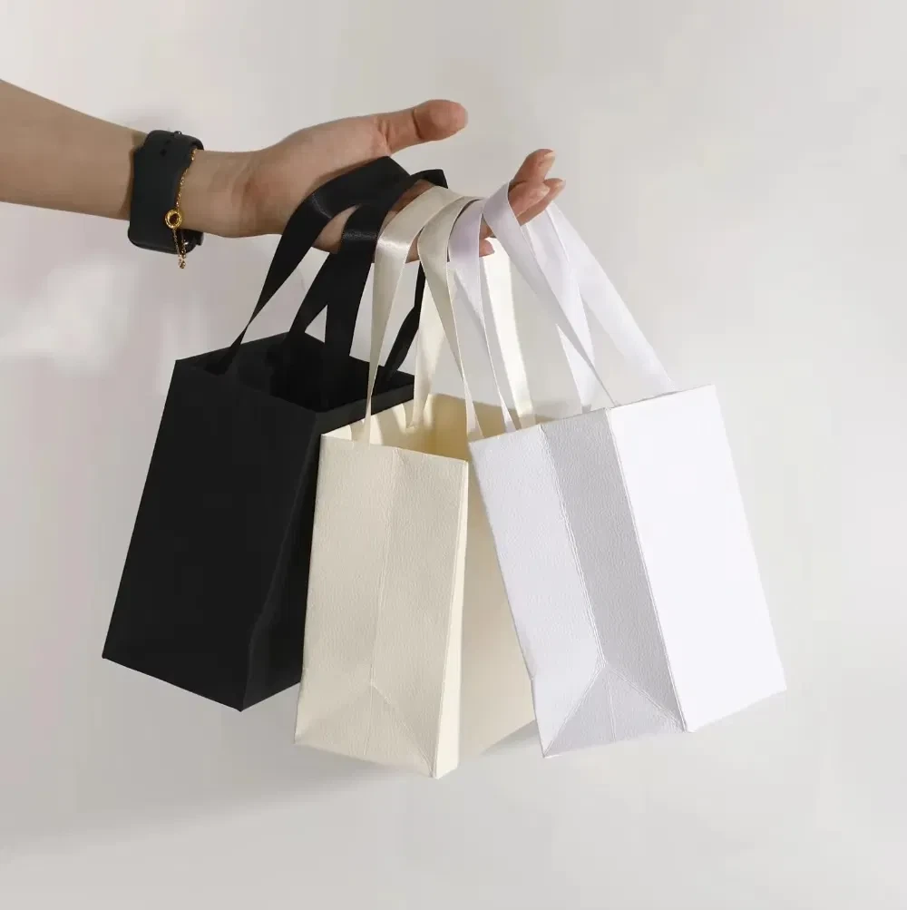 カスタムプリントロゴ再利用可能丈夫なアートペーパーブティック包装バッグリボンハンドルショッピングギフトバッグ価格 1