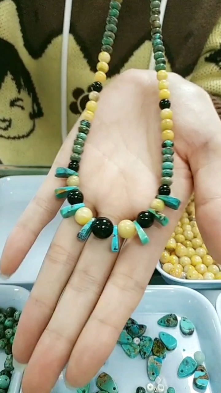 Ин гарданбанди фирӯзӣ дорои сангҳои занбӯри асал ва оникси сиёҳ мебошад. Вимпелҳои ороишии туркуаз бо шакли беназири ҷуворимакка 9