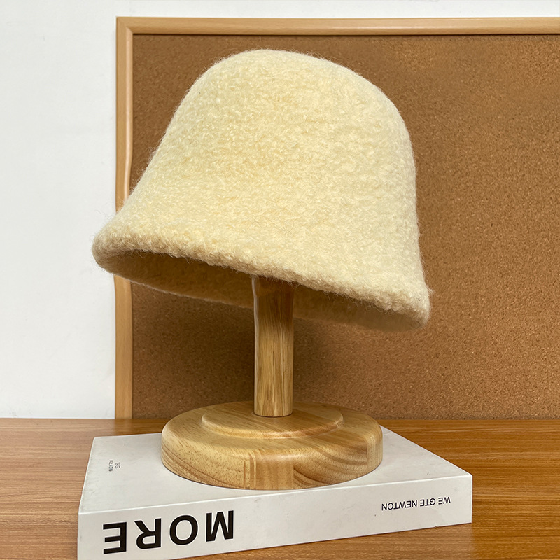 Pale yellow textured bucket hat with a rounded crown on a wooden display stand.