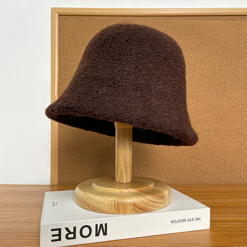 Dark brown textured bucket hat displayed on a wooden stand.