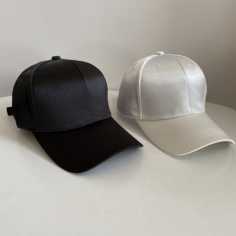 Black and white satin baseball caps shown together from the front