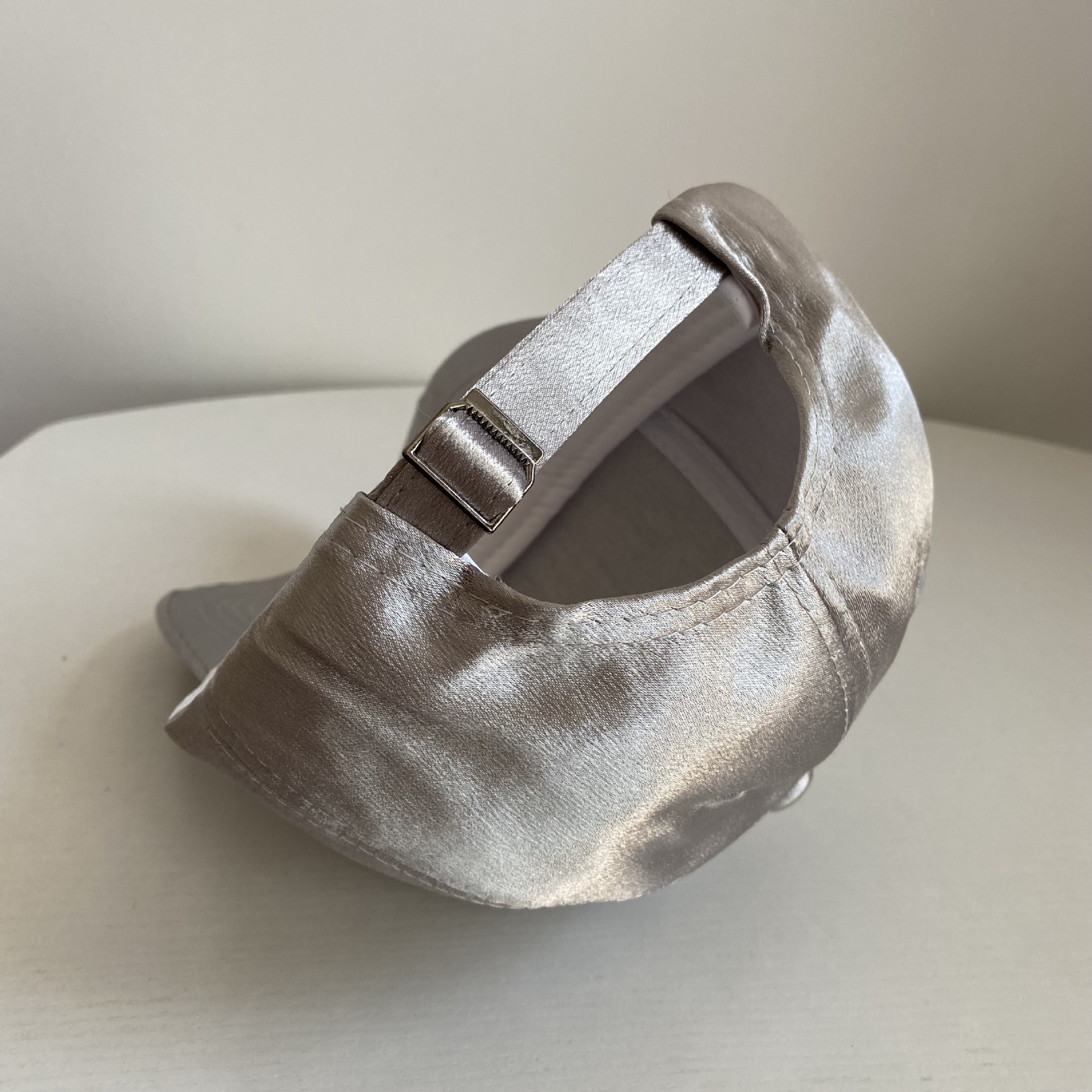 Rear view of a champagne satin baseball cap with an adjustable back strap