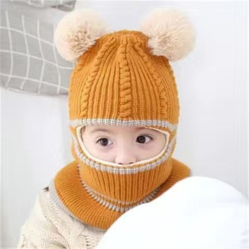 Toddler wearing a mustard yellow cable knit beanie with twin pom-poms and extended neck coverage.