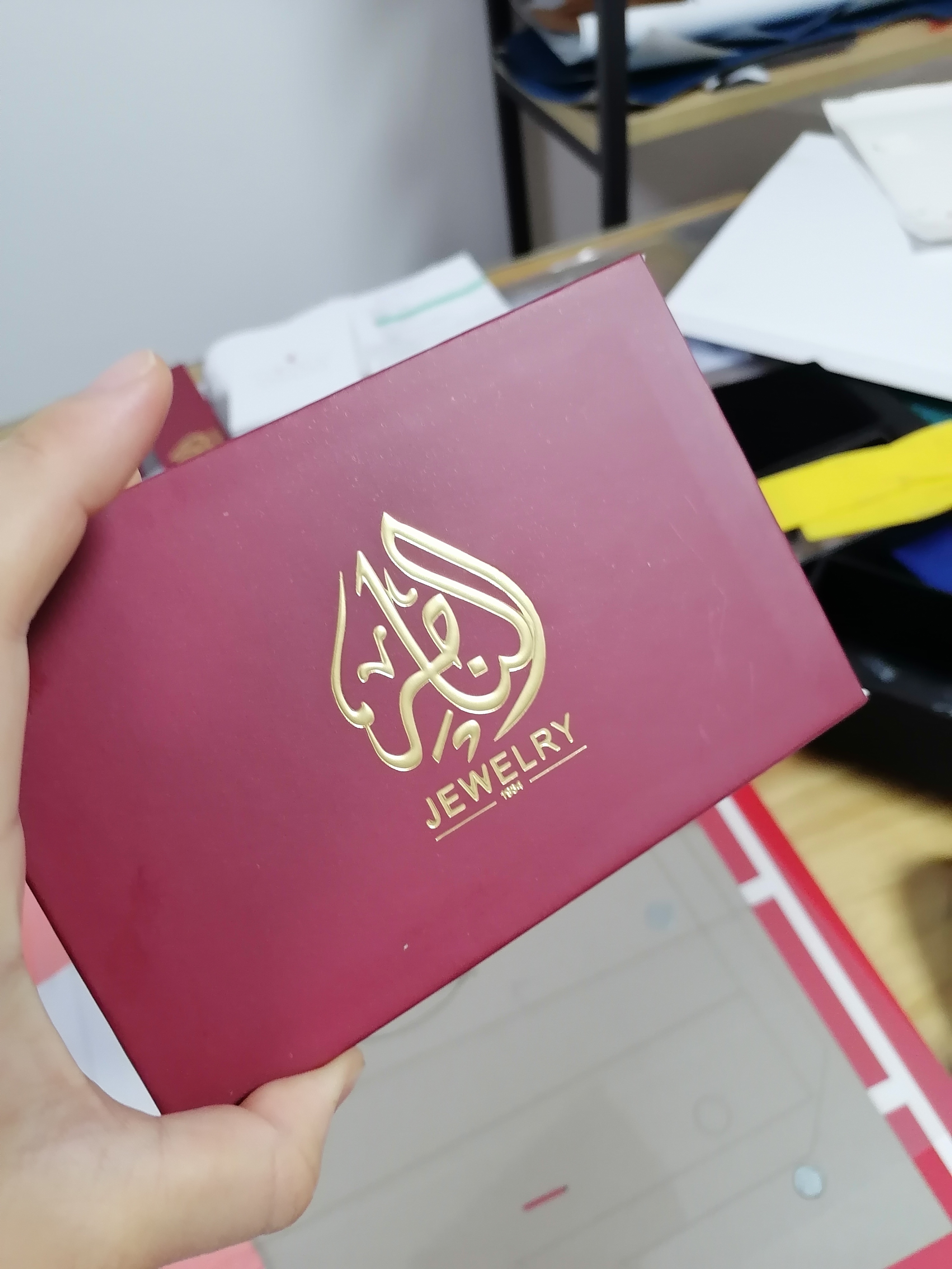 أناقة حمراء مع لمسة من الذهب: علبة السوار ذات الشعار المنقوش والذهبي