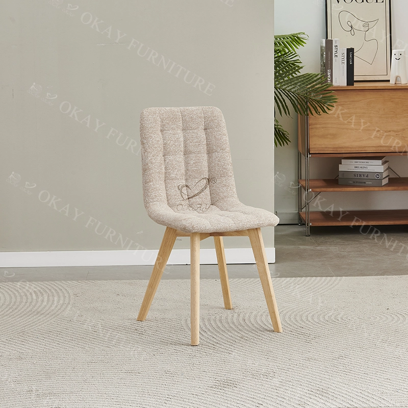 Silla de comedor nórdica moderna, patas de madera clara, respaldo tapizado en tela beige capitoné. 1