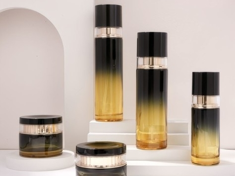 Set de envases para el cuidado de la piel en degradado negro-ámbar con tapas negras brillantes | Frascos de 120/100/40 ml y tarros de 50/30 g para líneas antiedad de alta gama 1